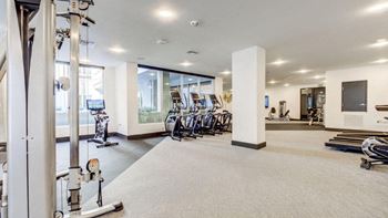 a gym with cardio machines and a tv on the wall
